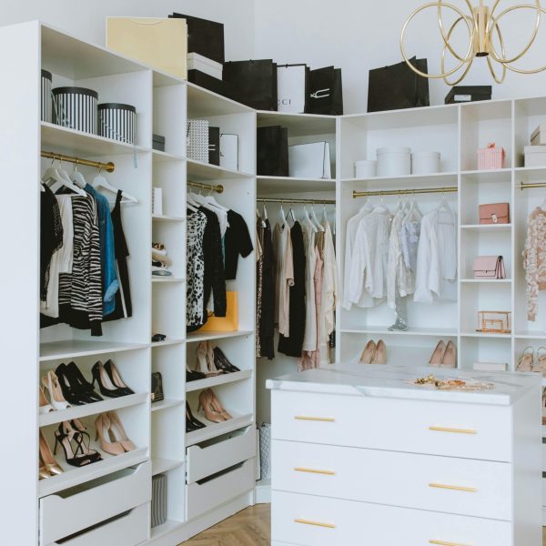 A stylish walk-in closet featuring luxury clothing, shoes, and accessories, with elegant shelving and chandeliers.